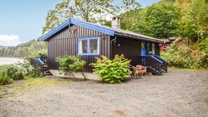 A cabin with a blue roof and a chimney, surrounded by greenery and a lake. - 3 bedroom awesome home in Vikersund (Vikersund)