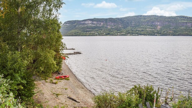 A lakeside view with a dock, kayaks, and a small table with chairs. - 3 bedroom awesome home in Vikersund (Vikersund)