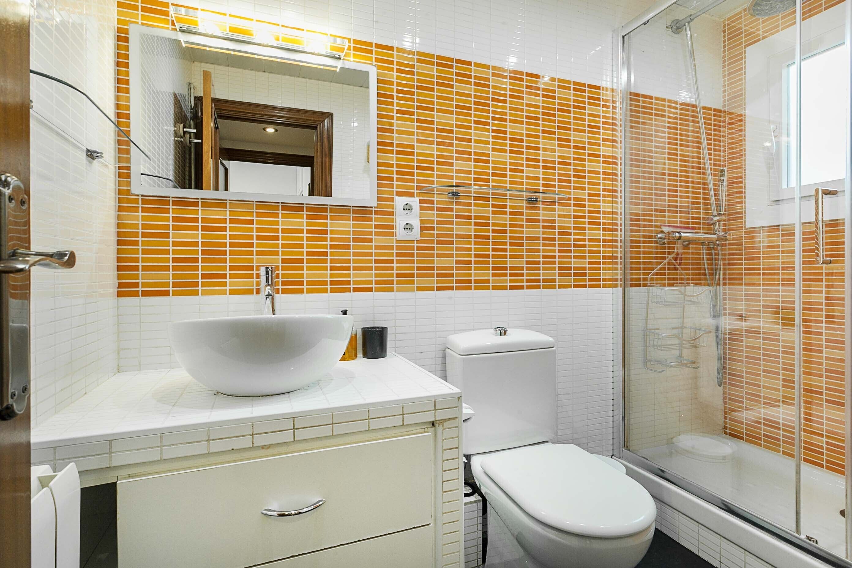 Een badkamer met een witte wastafel, toilet en douchecabine.