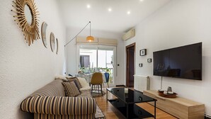 A living room with a striped sofa, a coffee table, a TV, and a wooden cabinet.
