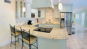 Eine moderne Küche mit Granit Arbeitsplatten, Edelstahlgeräten und Barhocker.