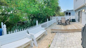 Ein Garten mit Holzterrasse, weißem Zaun und Gartenmöbeln.
