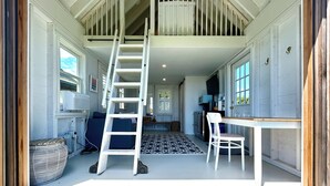 A staircase leading to a loft, a dining area with a table and chairs, and a kitchen area with cabinets and a countertop.