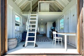 Un escalier menant à une mezzanine, un coin repas avec une table et des chaises, et un espace cuisine avec des placards et un plan de travail.