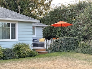 A house with a porch, a white picket fence, and a hedge.
