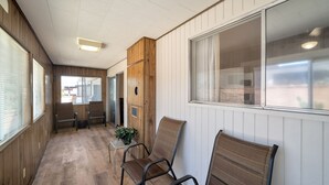 A hallway with wooden paneling, a sliding glass door, and a seating area with chairs and a small table.