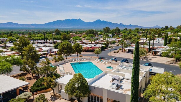 A resort with a swimming pool, multiple buildings, and a mountainous backdrop.
