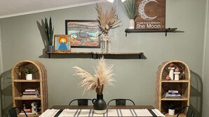 Ein Essbereich mit Holztisch, schwarzen Stühlen, Deckenventilator und dekorativen Wandschränken.
