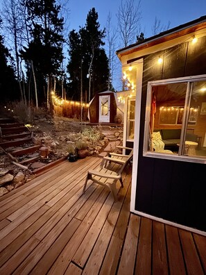 A wooden deck with outdoor seating, a small shed, and string lights. - Some Place Beneath the Moon- Black Hawk (Black Hawk)