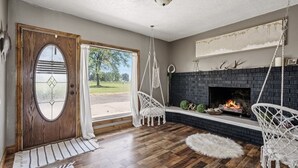 Une pièce avec une porte en bois, une cheminée et une vue sur l’extérieur.