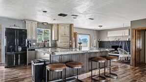 Une cuisine spacieuse avec un grand îlot central, des tabourets de bar et un réfrigérateur noir.