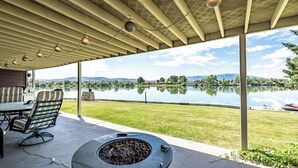 Une terrasse extérieure équipée d’un barbecue, de sièges et offrant une vue sur un lac.