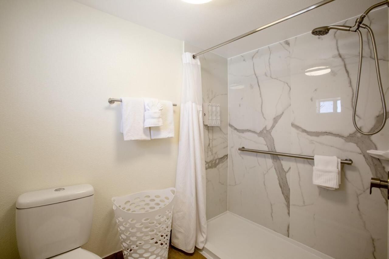 A bathroom with a toilet, a shower with a glass door, and a towel rack.