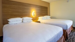 A hotel room with two beds, each with white linens and pillows, a wooden headboard, and a wall-mounted light fixture. - Kitchenette Room in Sedona at Thunder Mountain (Sedona)
