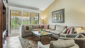 Un salon comprenant un canapé, des fauteuils, une table basse et un tapis à motifs.
