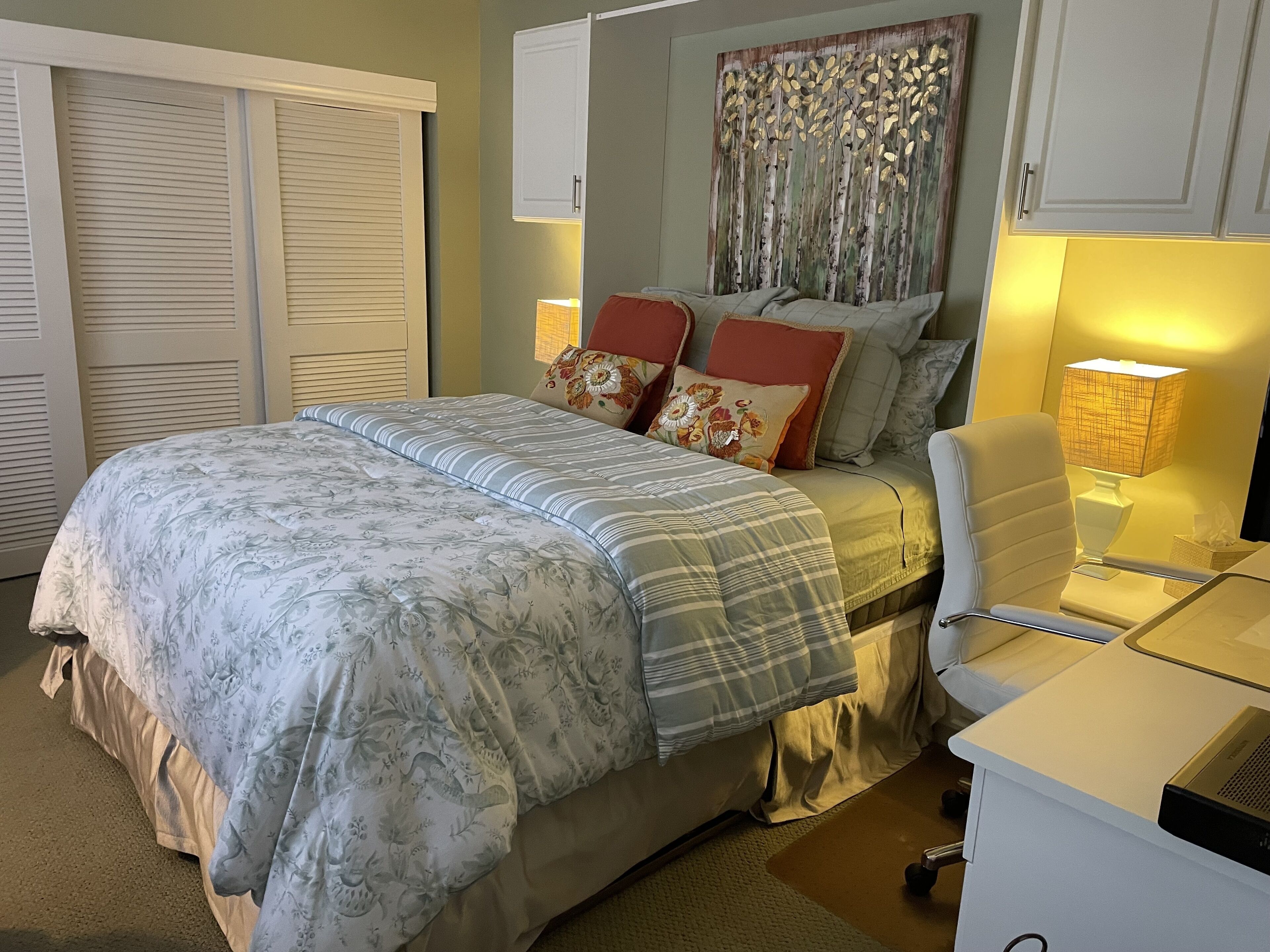 Ein Schlafzimmer mit Bett, Schreibtisch, Stuhl und Kleiderschrank.