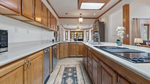 A spacious kitchen with wooden cabinets, a large island, and a skylight. - Lakefront Estate • Sleeps 23 • Firepit & Kayaks (Seguin)
