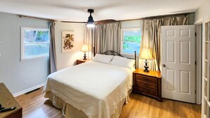 Een slaapkamer met een bed, twee nachtkastjes met lampen, een deur en een raam.
