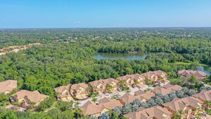 A residential area with houses, a lake, and surrounding greenery.