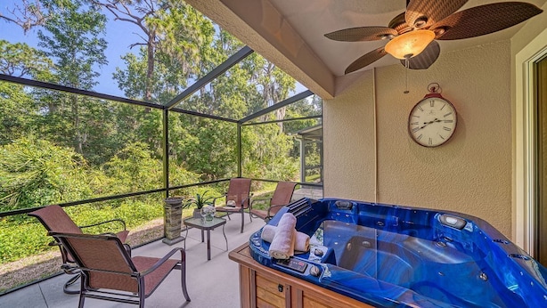 A balcony with a hot tub, chairs, and a clock.