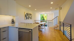 Eine moderne Küche mit einer zentralen Kochinsel, Holzböden und einer Treppe zu einer oberen Etage.
