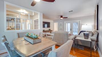 Un salon moderne comprenant un coin repas, un canapé, une table basse et un ventilateur de plafond.