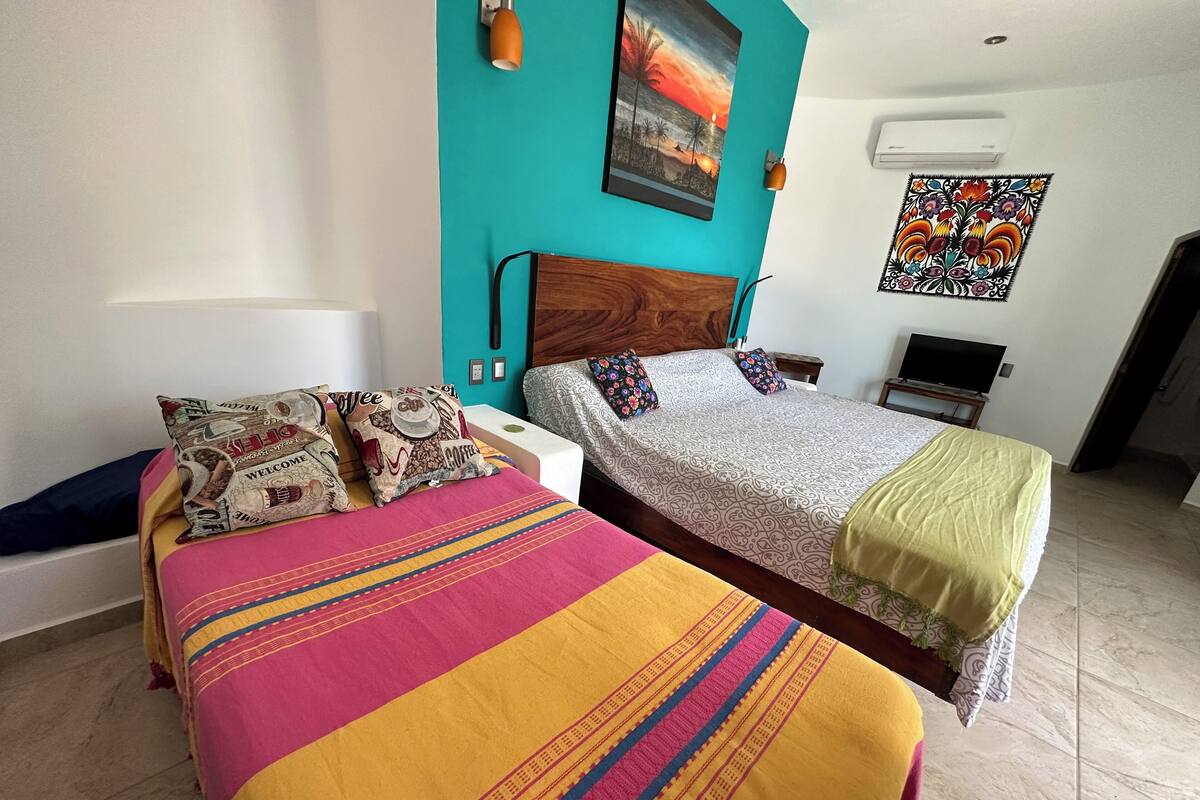 Quarto de hotel com duas camas, uma televisão e um quadro na parede.