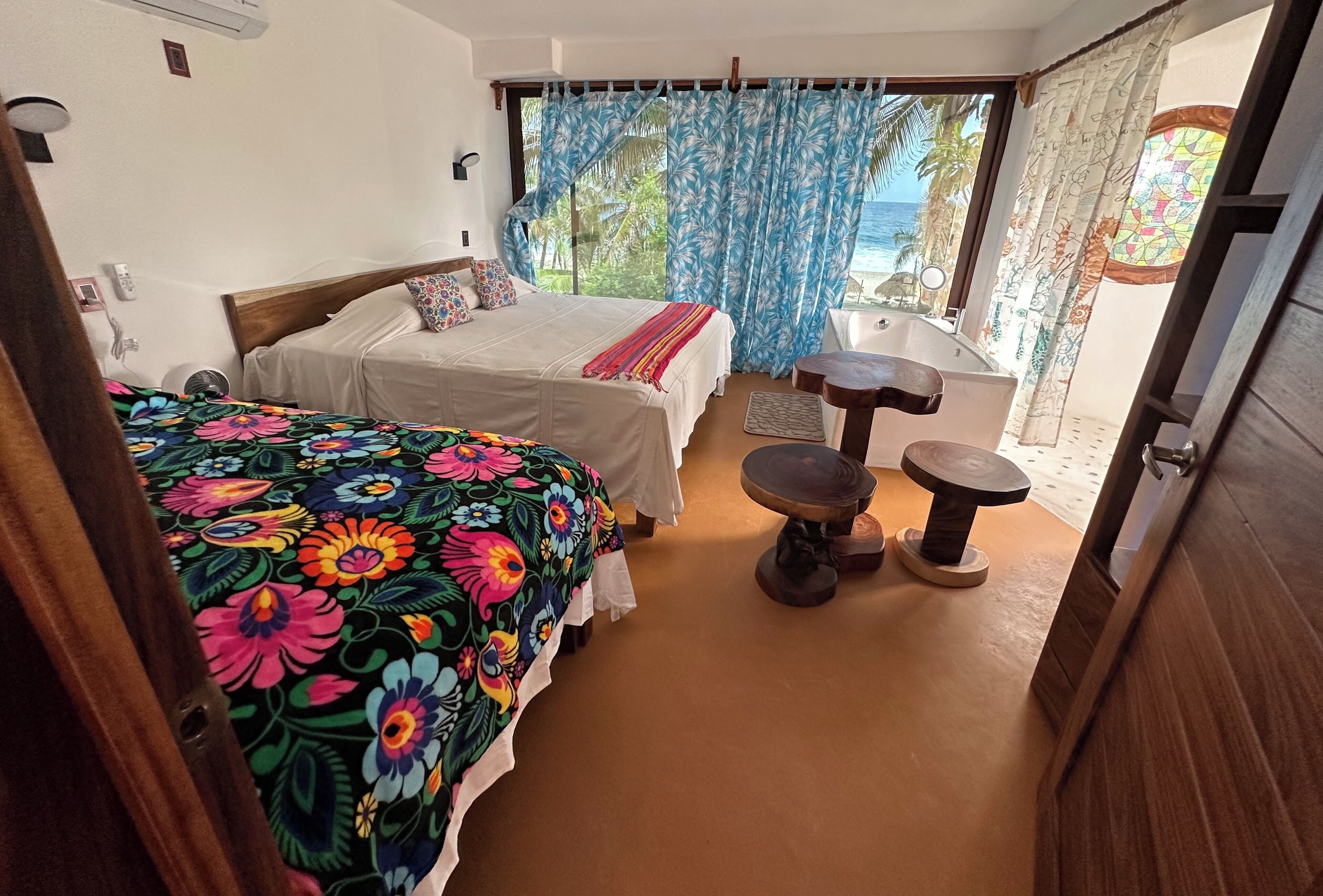 Une chambre avec deux lits, une petite table et vue sur l ’océan.