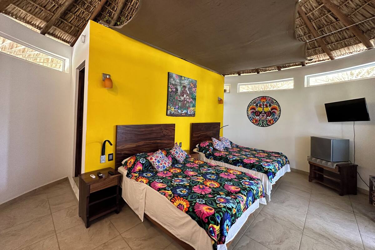 Quarto com duas camas, televisão e um quadro na parede.