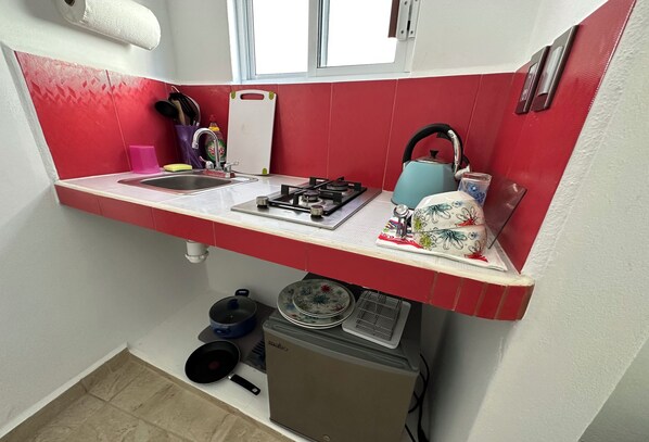 A compact kitchen with a gas stove, sink, and a small refrigerator.