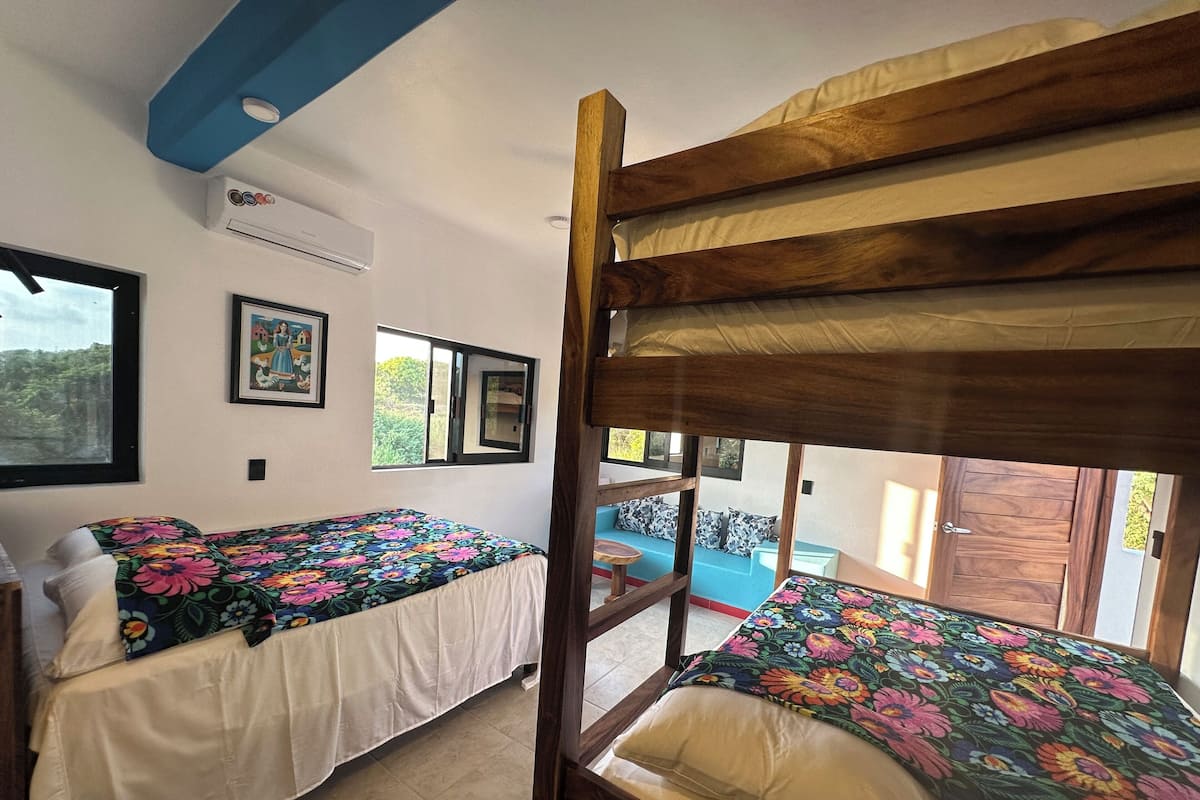 Quarto com duas camas beliche, uma janela e porta para área externa.