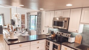 A modern kitchen with white cabinets, stainless steel appliances, and a black countertop. - Stylish, Remodeled Condo - Pool, Tennis, Golf - (Palm Springs)