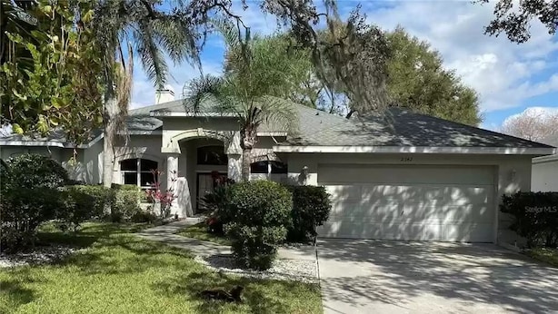 A residential house with a garage, a driveway, and a well-maintained lawn. - Cheery 4 Bedroom Pool Villa (Valrico)