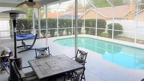 A covered patio with a pool, outdoor furniture, and a view of the neighborhood. - Cheery 4 Bedroom Pool Villa (Valrico)