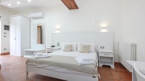 Une chambre à coucher comprenant un lit, des tables de chevet, une armoire et un appareil de climatisation.