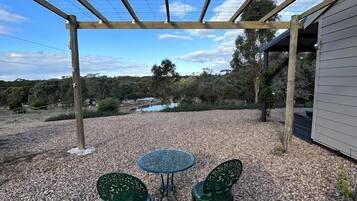 Relax in a serene outdoor space with a pergola, gravel surface, and comfortable seating for two.