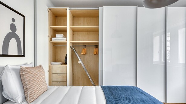 Un dormitorio con cama, armario y ropero con estantes y espacio para colgar.
