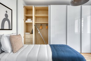 Un dormitorio con cama, armario y ropero con estantes y espacio para colgar.