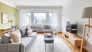 Una sala de estar moderna con un sofá gris, una mesita, un televisor y una lámpara.