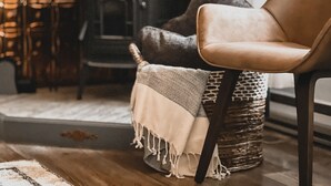 Une pièce chaleureuse avec un canapé, un panier en osier et une couverture.