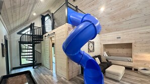 Un intérieur en bois avec un toboggan bleu, un escalier et un espace détente.