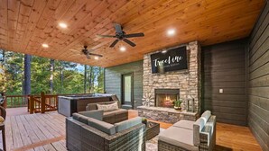 Une terrasse extérieure accueillante, dotée de meubles en osier, d’une cheminée en pierre et d’un panneau indiquant « TreeLine Vacation Rentals ».