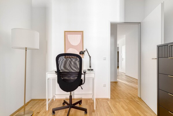 A modern office space with a desk, chair, lamp, and a framed picture on the wall.