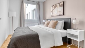 A modern bedroom with a bed, bedside table, and a window with curtains. - Luxe Mariahilf 2BR w/ Elevator, near Mariahilfer Straße (Vienna)