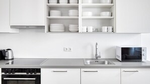 A modern kitchen with white cabinets, a stainless steel sink, a microwave, and a stove. - Luxe Mariahilf 2BR w/ Elevator, near Mariahilfer Straße (Vienna)