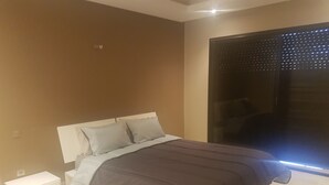A bedroom with a bed, a nightstand, and a large window with blinds. - Torque 111 (Marrakech)