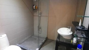 A modern bathroom with a glass-enclosed shower, a white toilet, and a black vanity with a sink. - Torque 111 (Marrakech)
