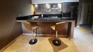 A modern kitchen with a central island, two bar stools, stainless steel appliances, and a recessed ceiling light. - Torque 111 (Marrakech)
