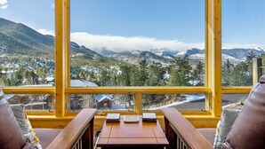 Een houten tafel met uitzicht op besneeuwde bergen en een stad door grote ramen.