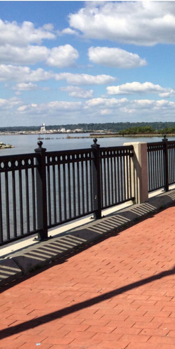 Stroll along the waterfront promenade with a scenic view of the body of water and a distant shoreline.